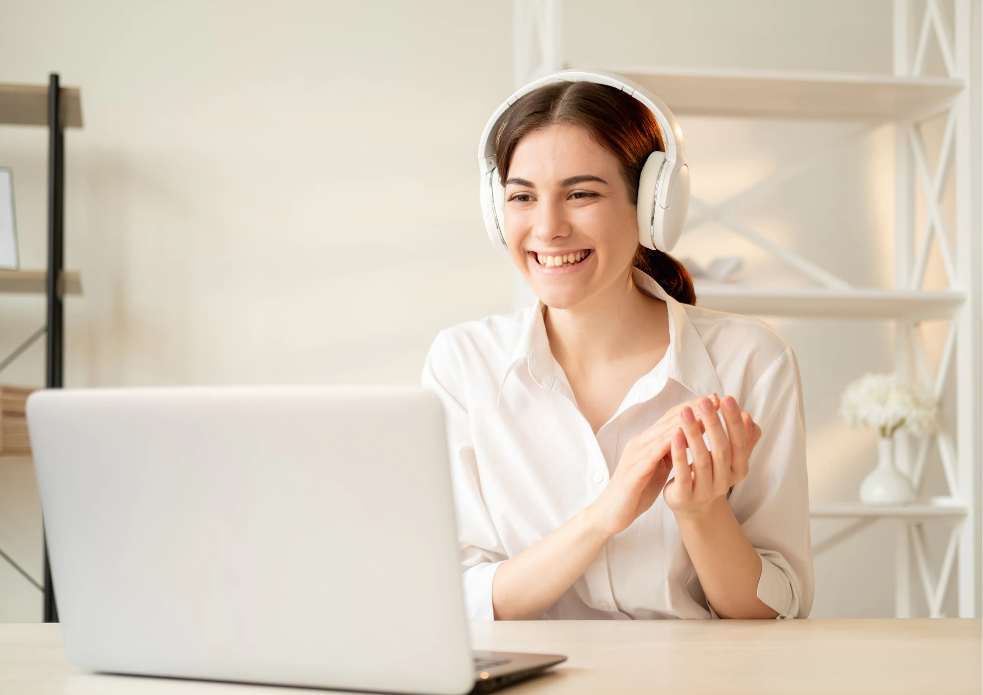 Une femme assise à son bureau devant son ordinateur qui sourit